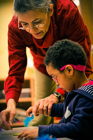 Therapist helping young boy identify different objects - image