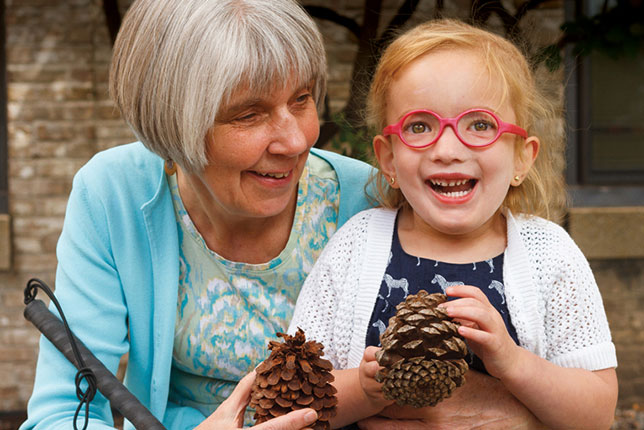 Woman and young girl holding pinecones and smiling with one another image