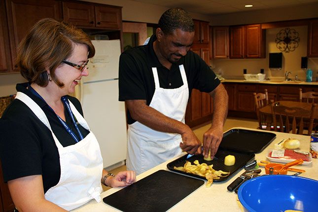 Man with instructor learning new kitchen skills - image