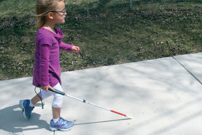 Child walking with cane.