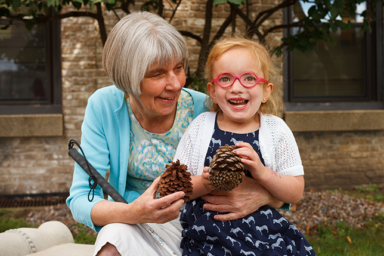 An older woman and young girl, both of whom are visually-impaired, in a happy embrace.