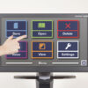 Clearview+ Speech screen. A number of icons are on the screen, and a hand reaches to touch them, demonstrating the touch screen.