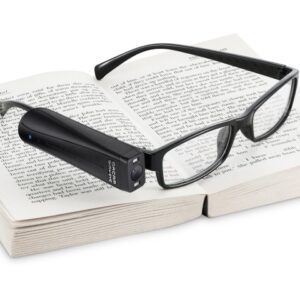 Orcam is seen connected to the side of a glasses frame. The glasses sit on top of a book.