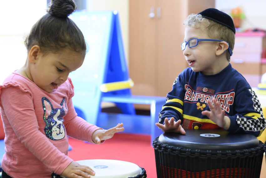 Two children playing drums in music therapy.