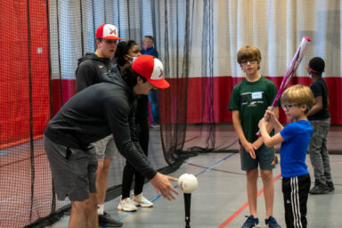 MSOE baseball player working with youth on batting skills.