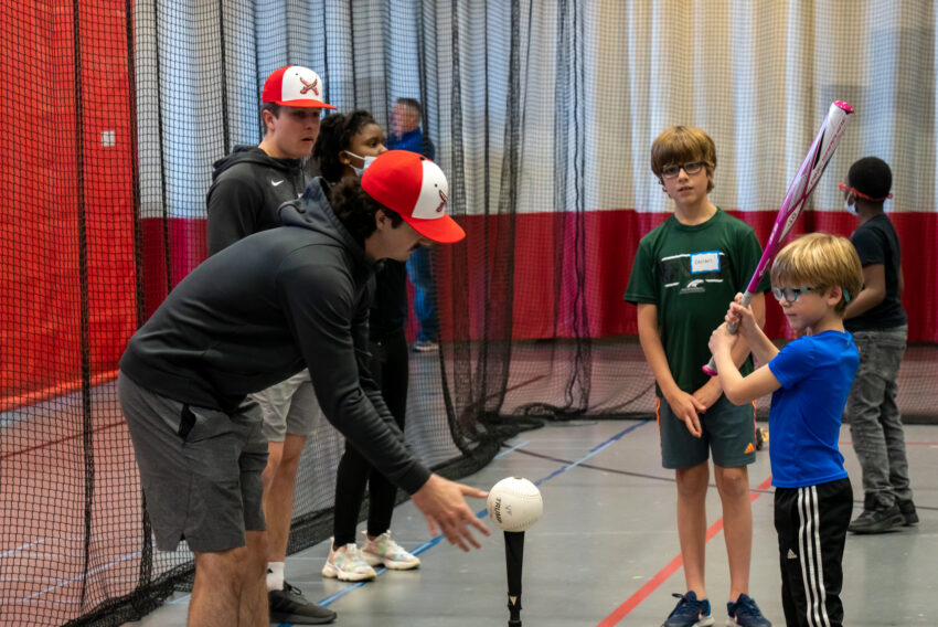 MSOE baseball player working with youth on batting skills.