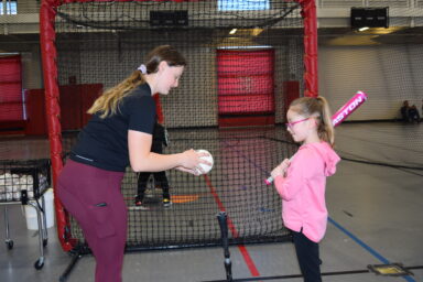 Volunteer working with youth on batting.