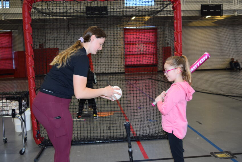 Volunteer working with youth on batting.