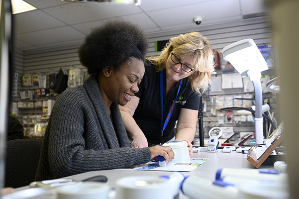 Image of store staff working with a customer on magnifiers.