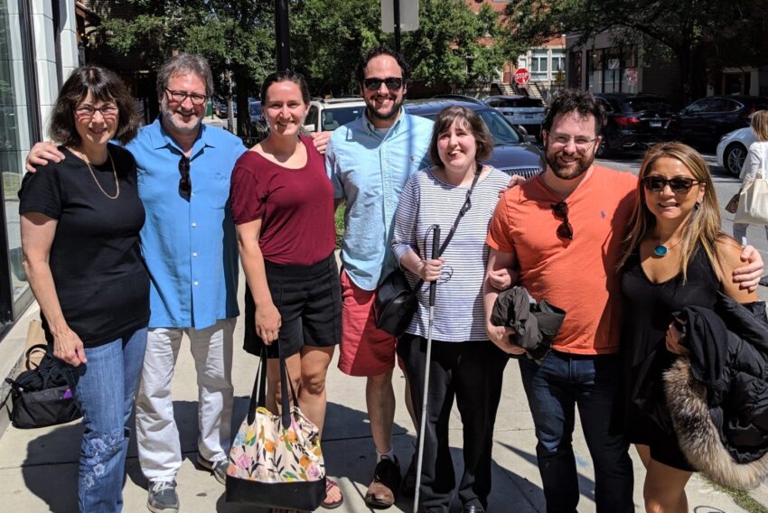 Eight members of the Moser-Kaplan Family pose for a photo in their neighborhood.