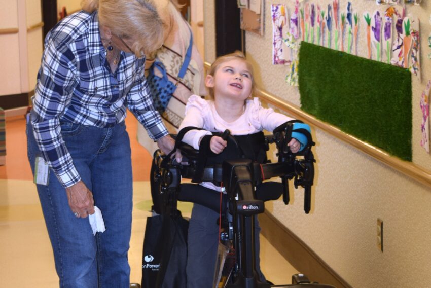 visually impaired girl in walking device with therapist helping