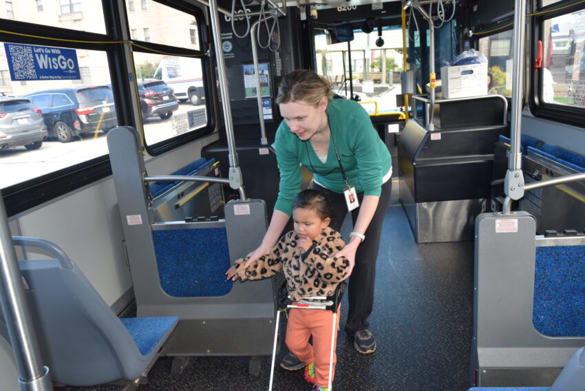 little girl with visual impairment with her walker and her teacher on city bus with a