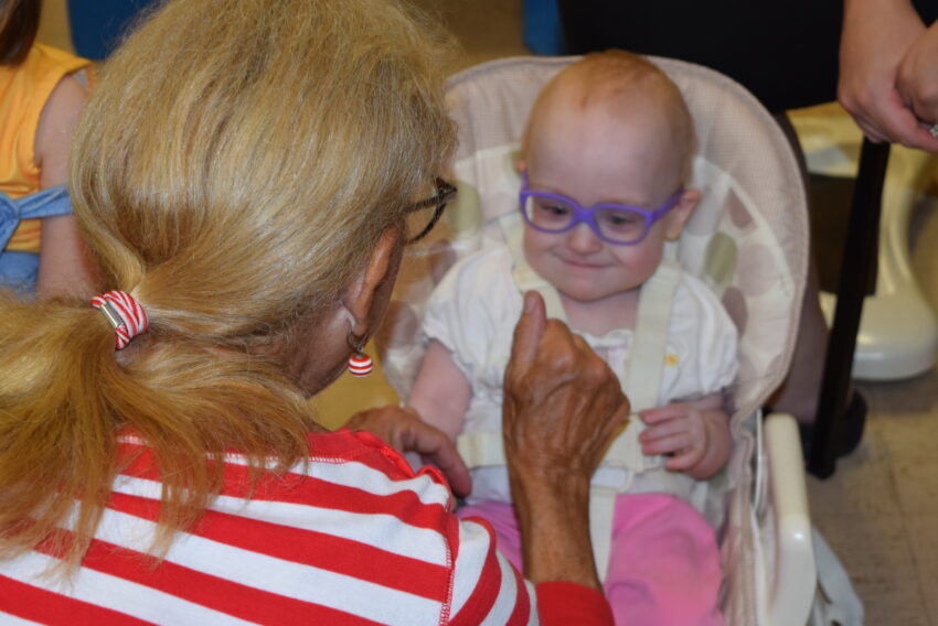 Baby smiling with glasses and teacher