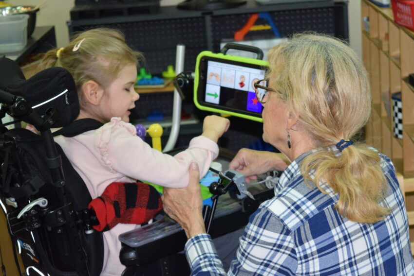 visually impaired girl in wheelchair working with teacher on computer