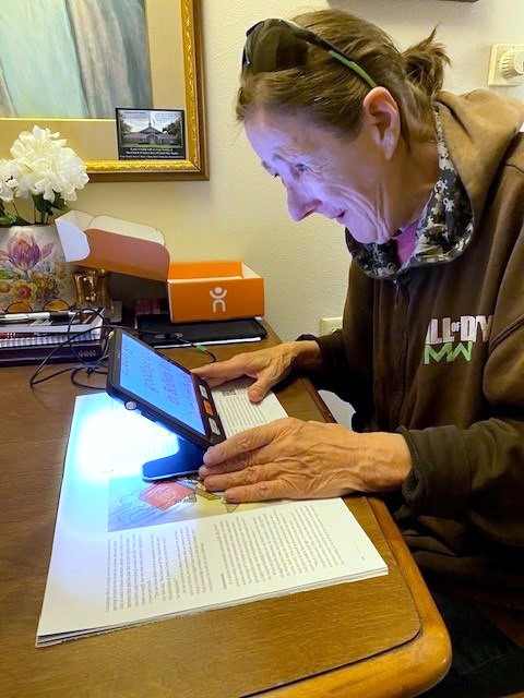 Woman using a handheld magnifier to read a paper