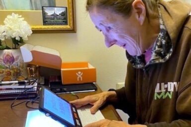 lady using handheld magnifier to read newspaper