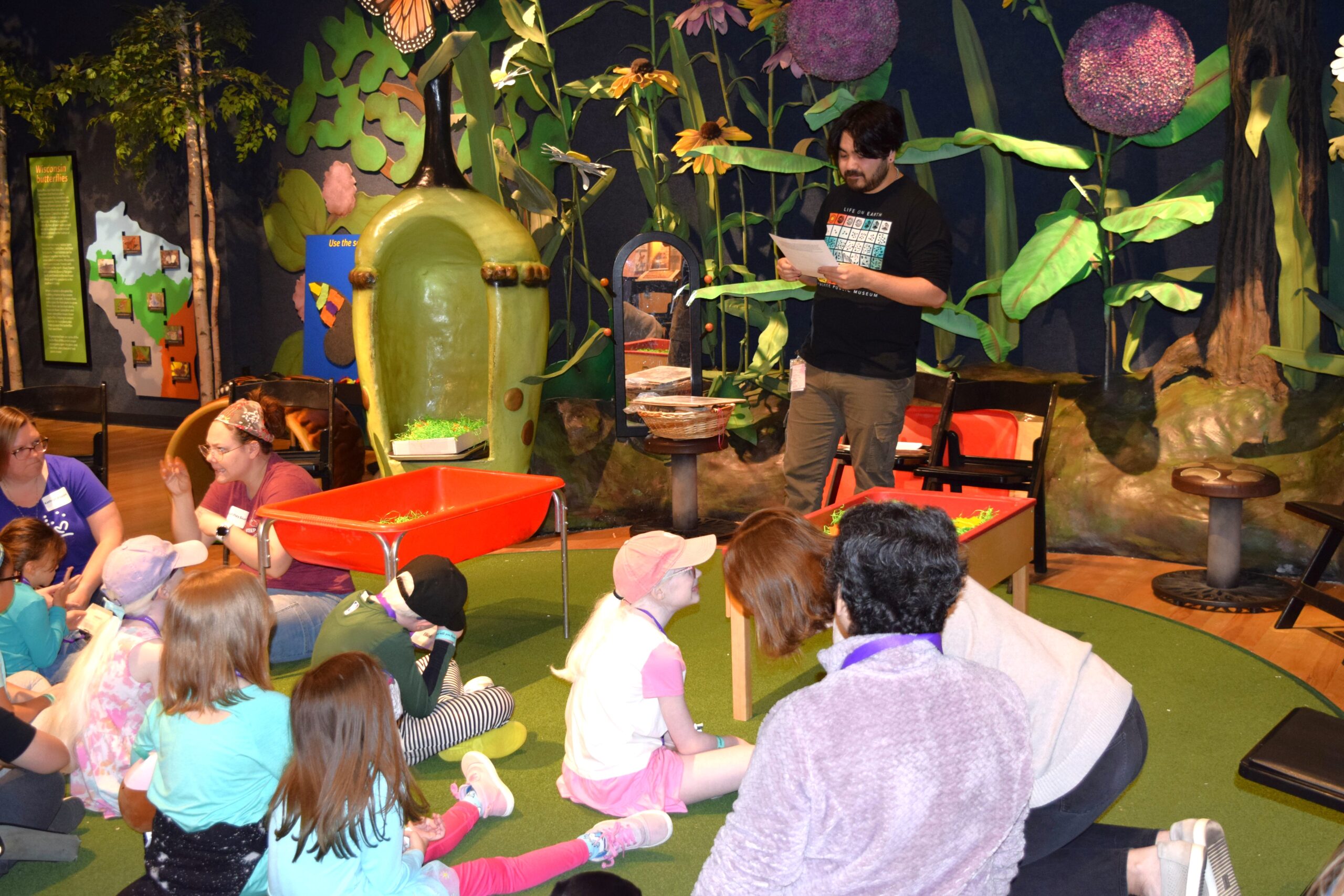 Kids gathered listening to a man reading a book