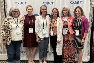 Women in a line smiling at the AER conference