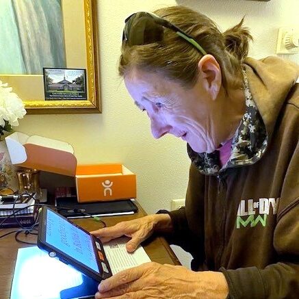 older woman is looking reading a paper with a screen reader