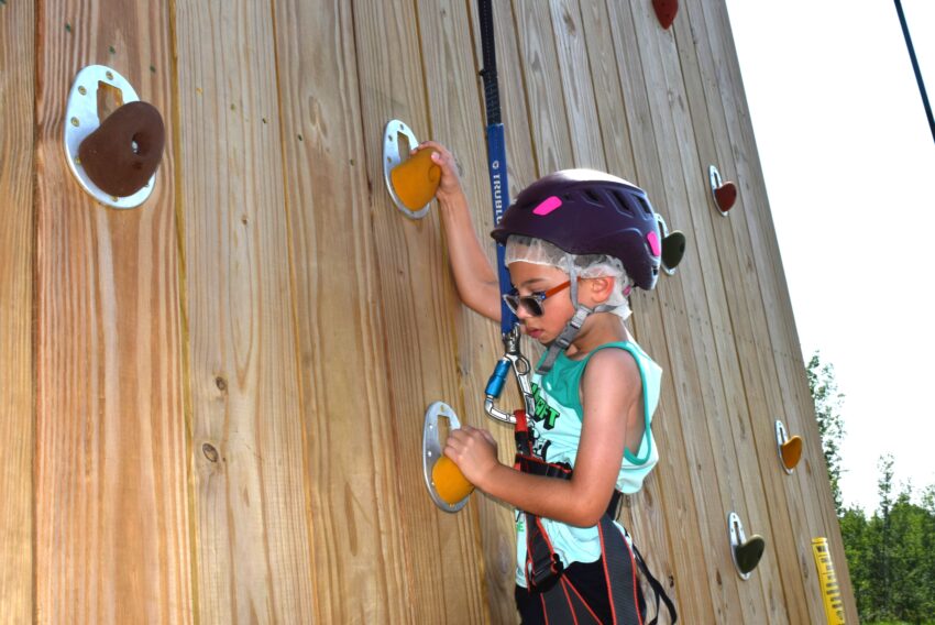 boy with helmet climbing up a rock wall