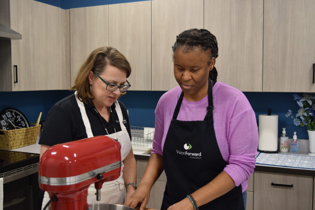 woman being guided by another woman in the kitchen