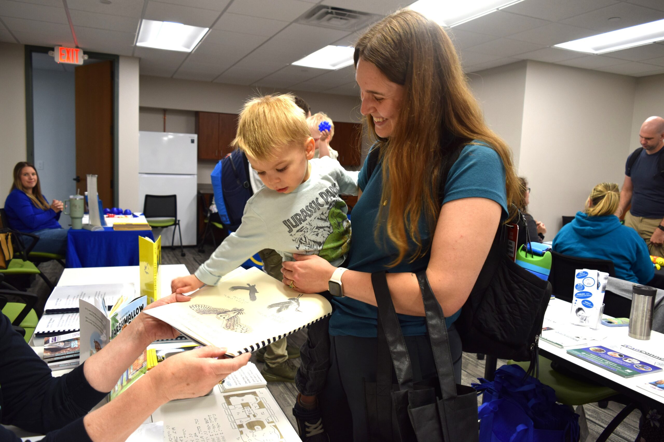 Child in mothers arms reaching to touch a book about birds of prey