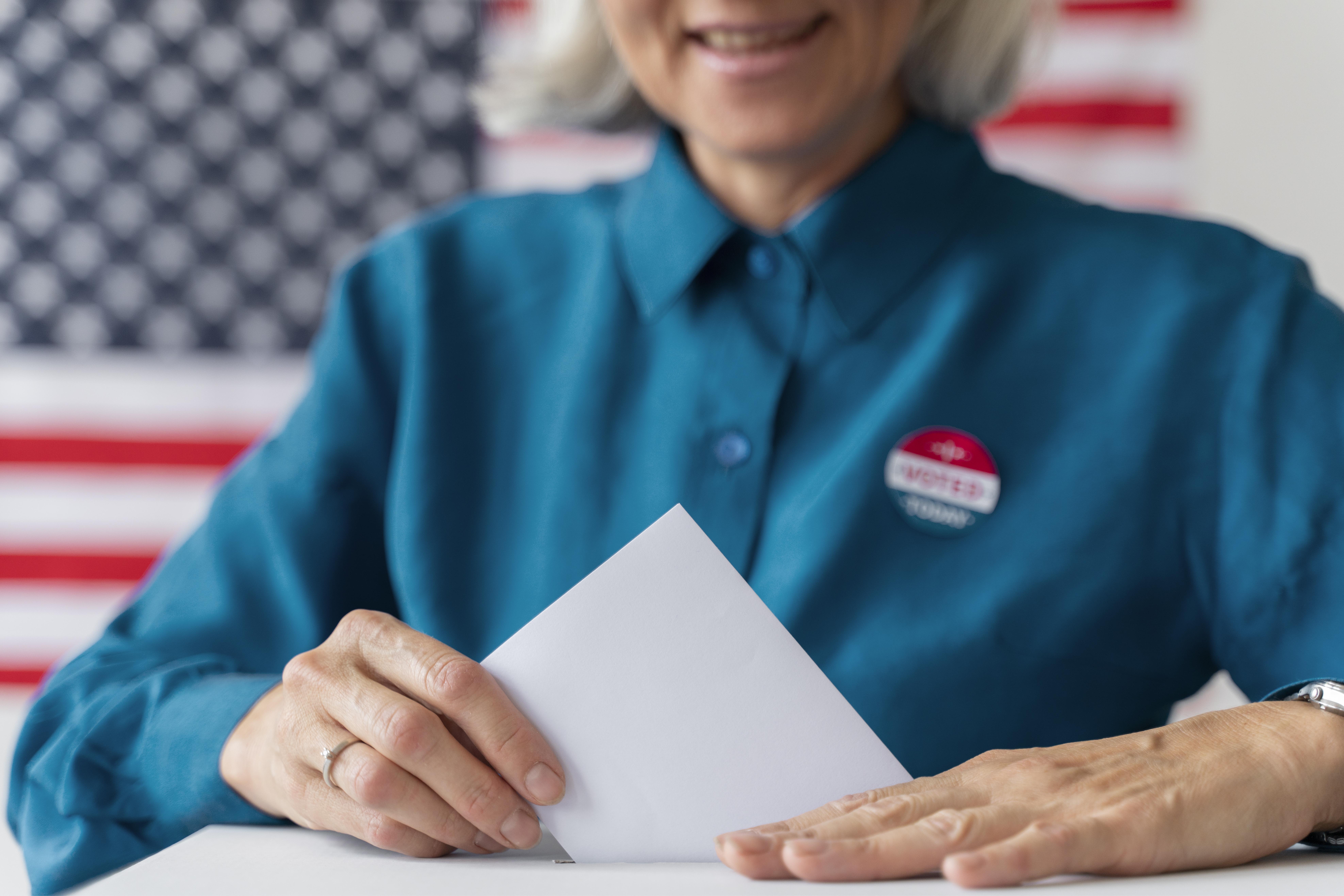 woman in front of voting box putting paper in it